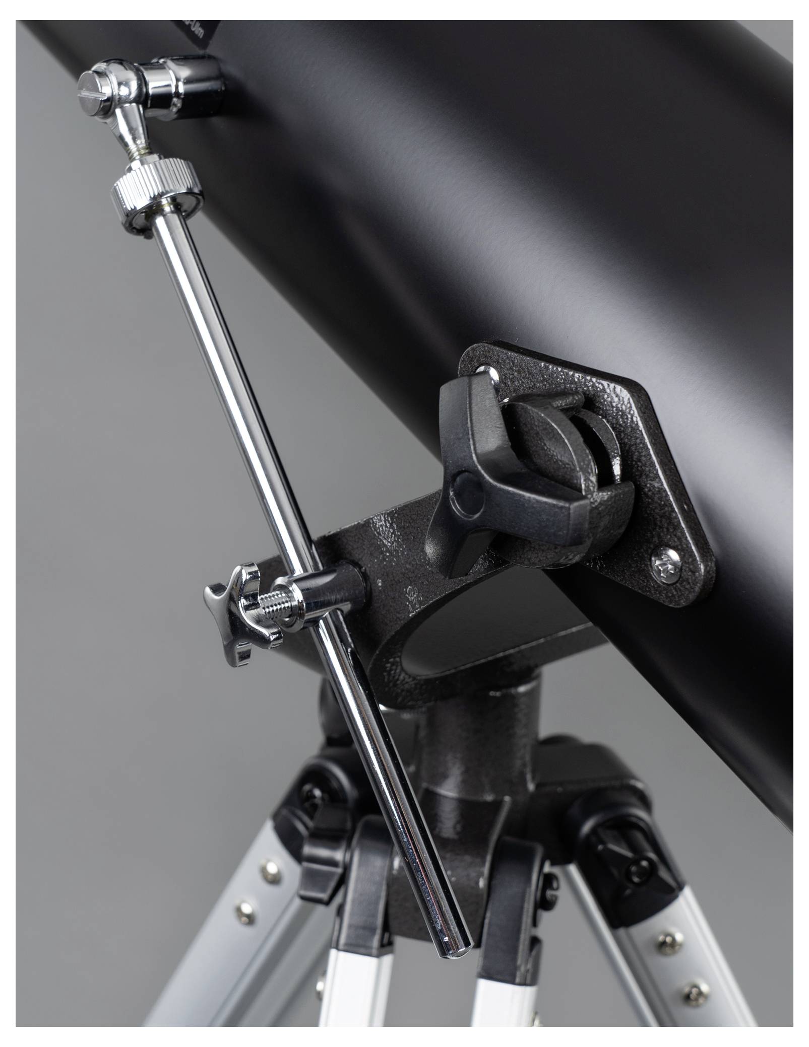 A telescope with a black tube and silver tripod. Focus on the adjustment mechanisms with rotary knobs and rods.