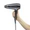 A hand is holding a black hairdryer positioned horizontally.