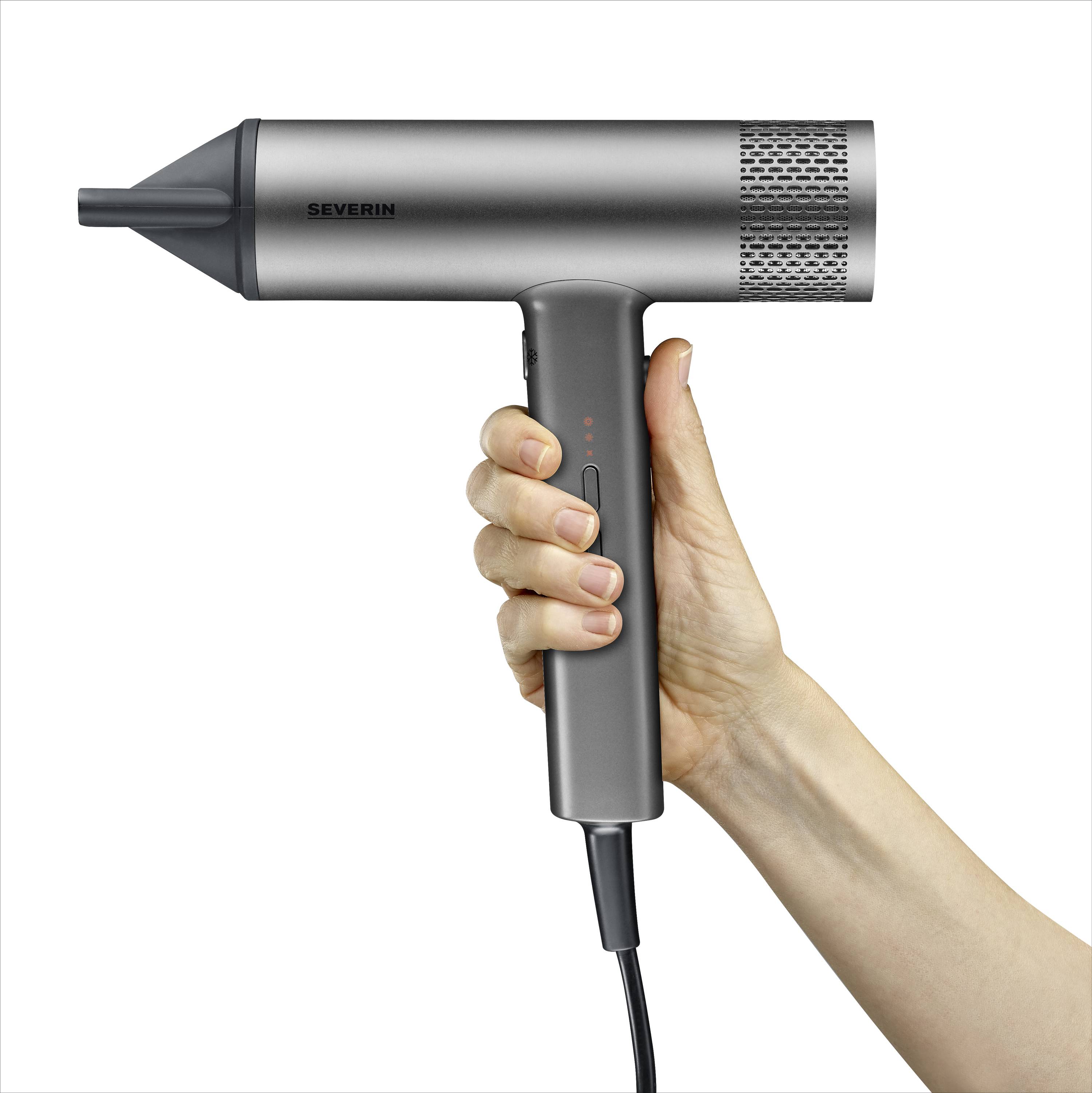 A hand is holding a grey hairdryer in a modern design. The cable hangs down. The device is switched on, with LED lights illuminating.