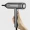 A hand is holding a grey hairdryer by Severin. The dryer has a modern design with a circular vent and multiple control buttons.