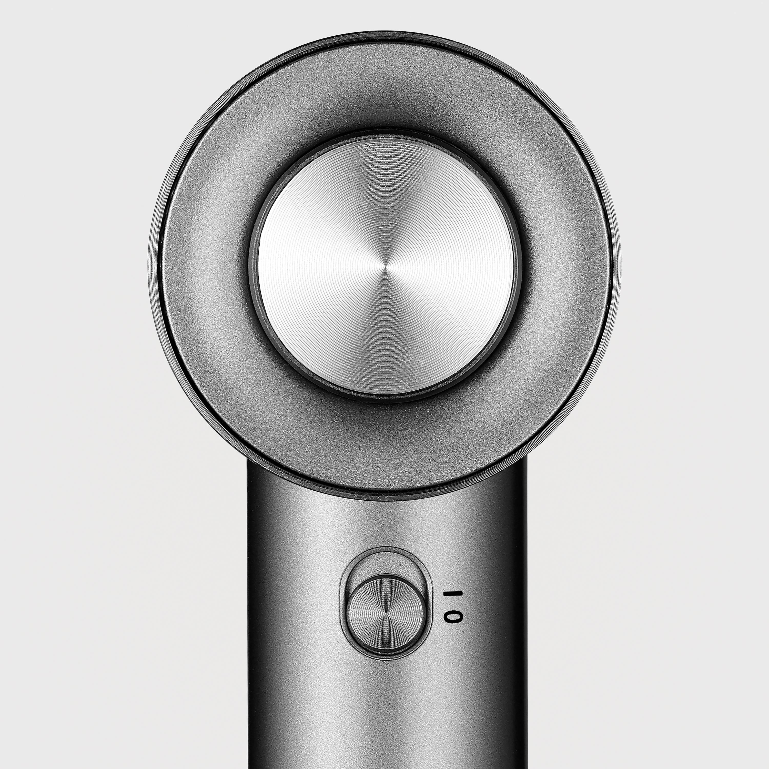A modern hairdryer with a round air outlet and a two-stage switch on a grey background.