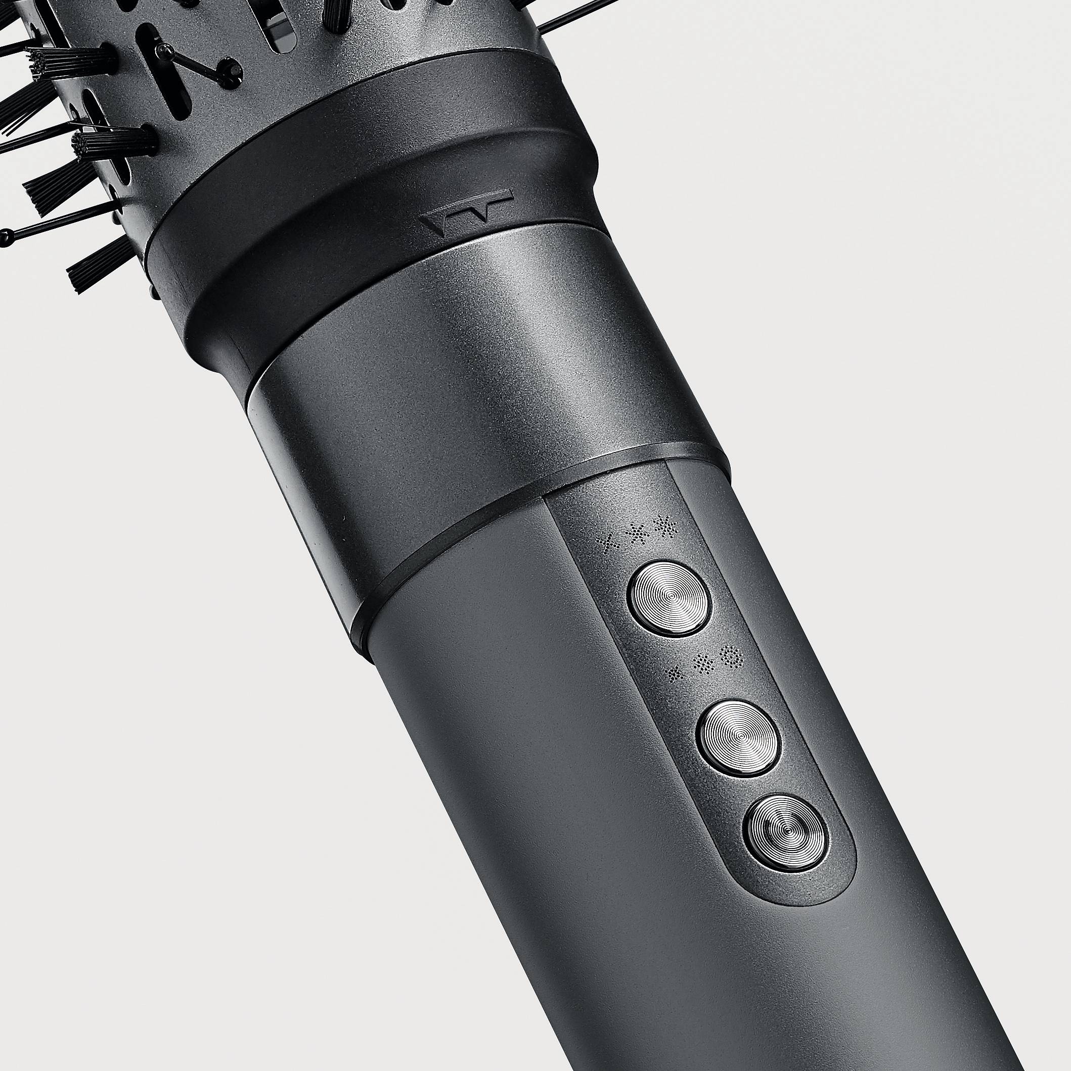 A black electronic hair styler with a removable brush attachment and control elements is positioned against a white background.