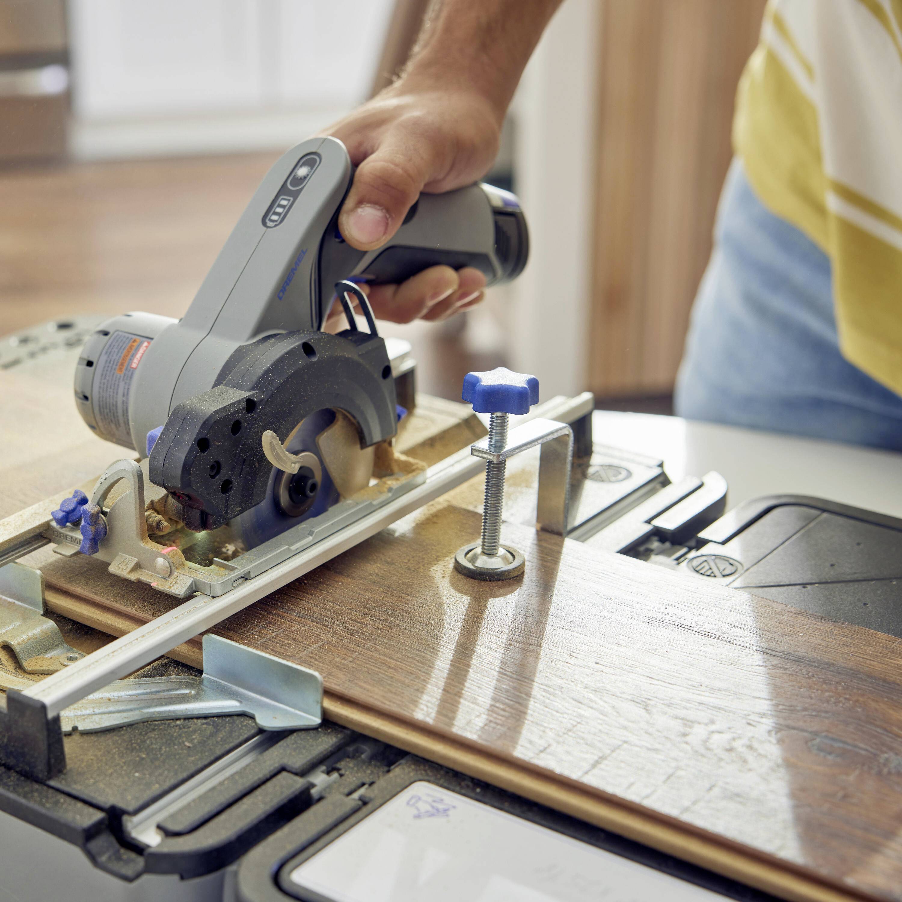 A person is using a circular saw to cut a piece of wood on a workbench. The environment appears craftsman-like and practical.