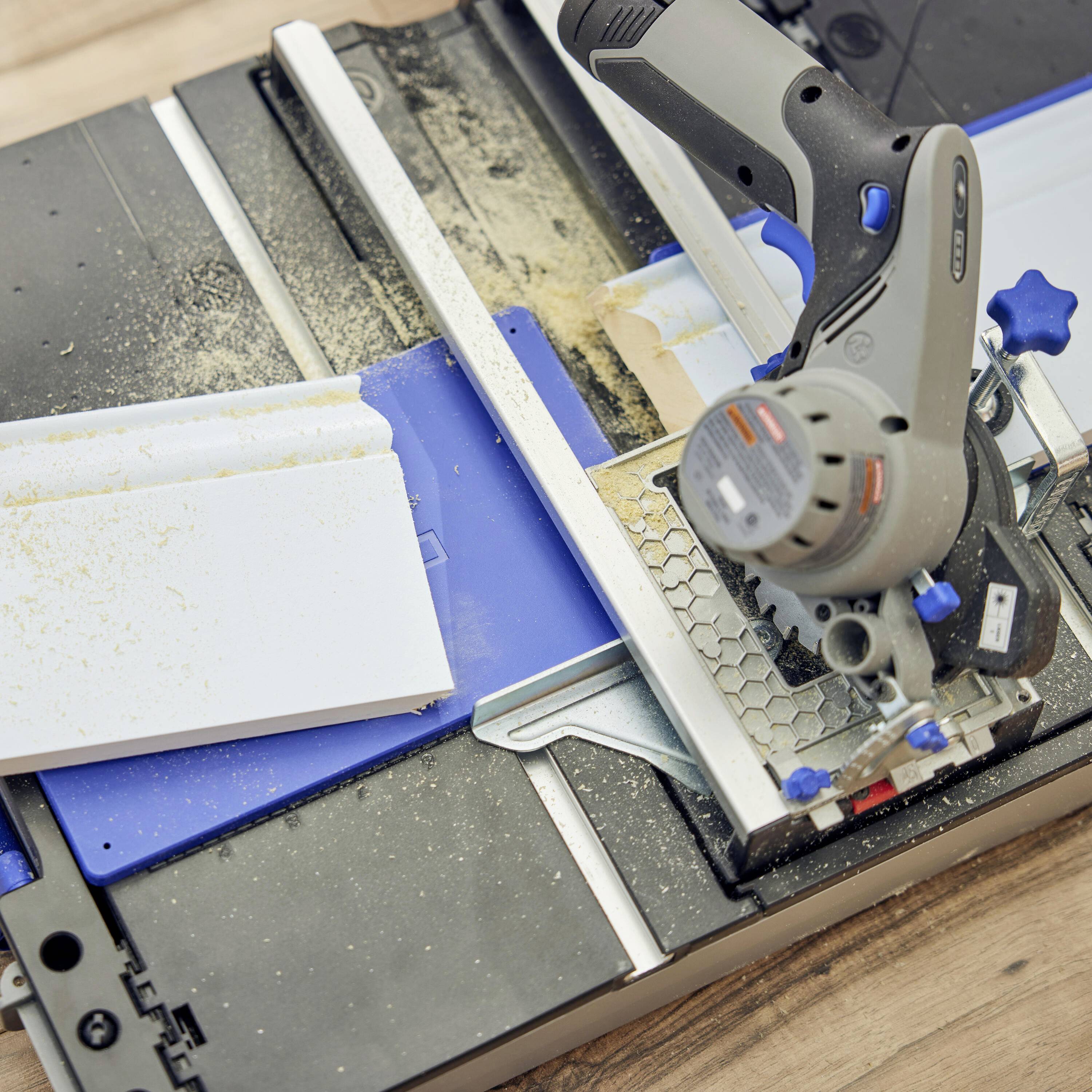 Circular hand saw in use on a wooden board, sawdust visible. Wood cutting process on a blue guide tool, focus on precision.