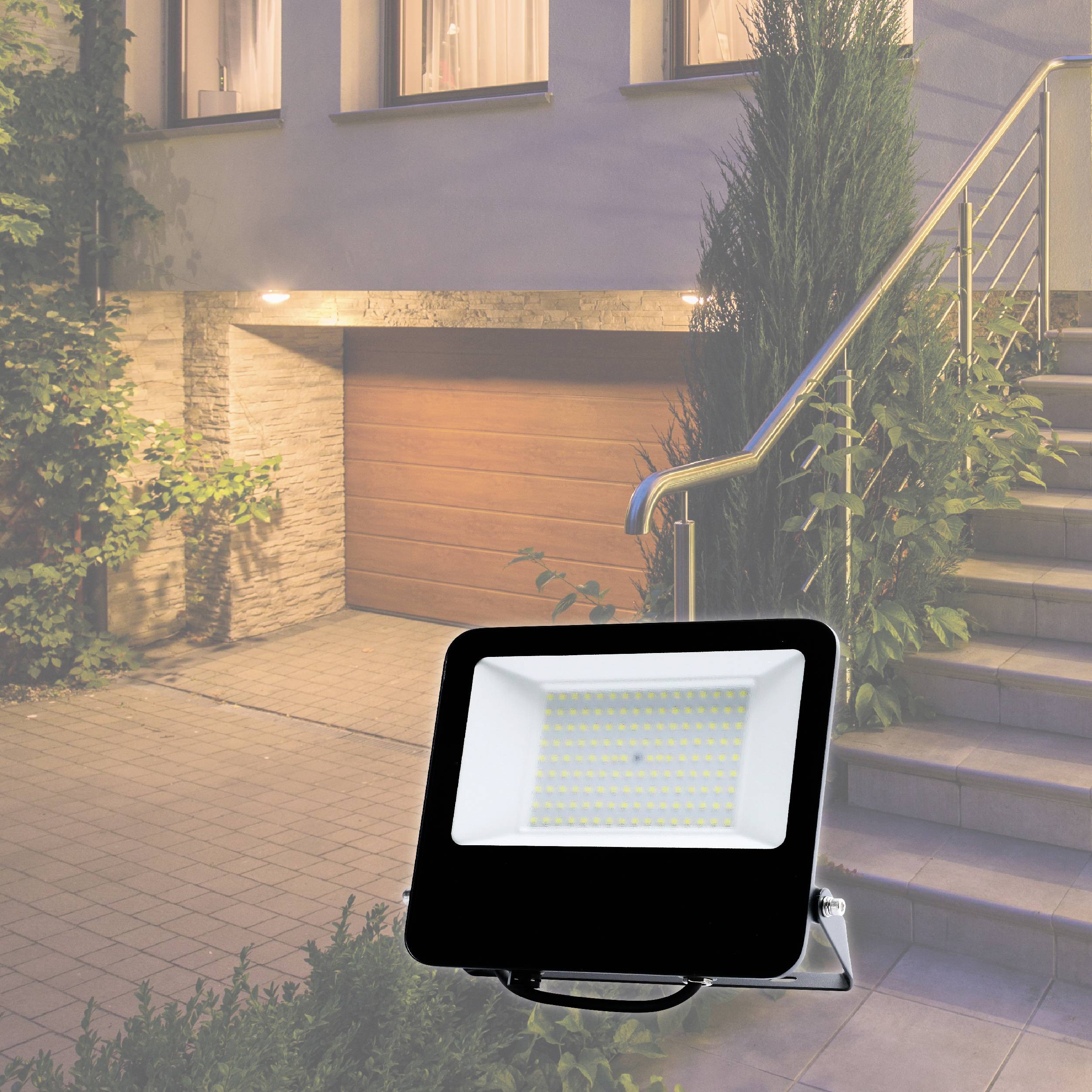 An LED floodlight illuminates the entrance of a house with a garage, steps, and plants to the side.