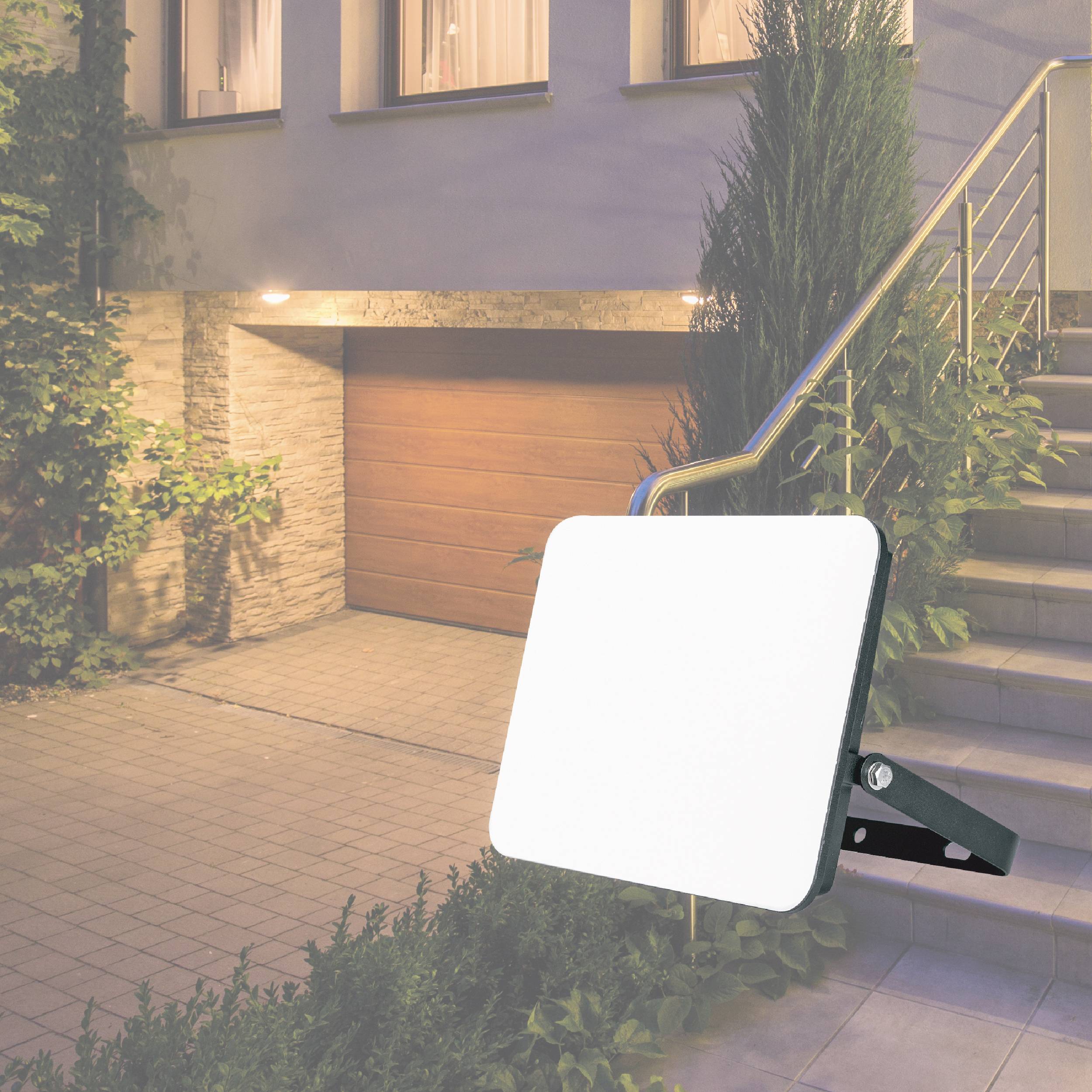 External lighting with a motion sensor on a house wall at night, illuminating the entrance area and stairs for security.