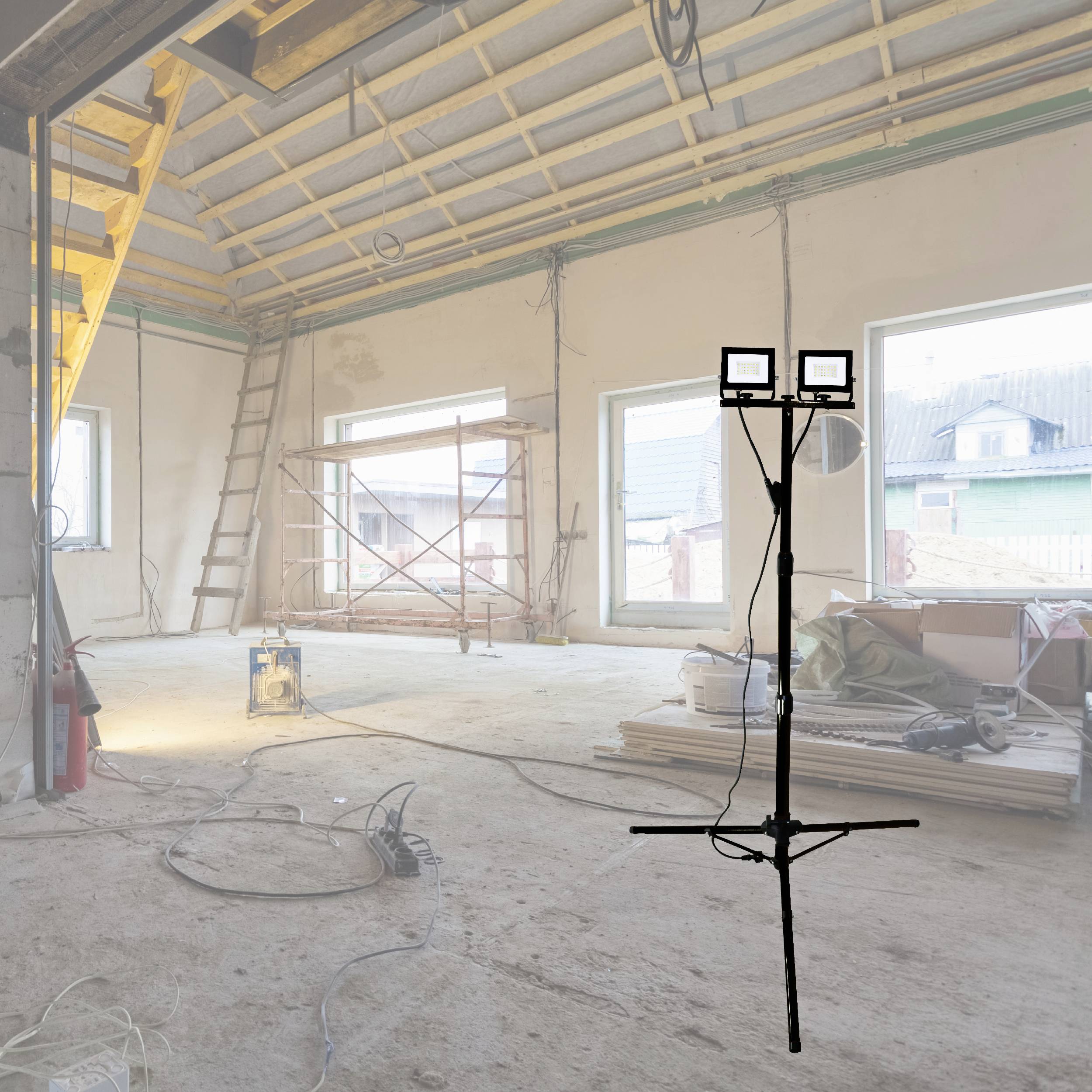 An empty room during construction with ladders, cables, and building equipment on the floor. Windows offer a view outside.
