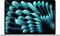 A laptop screen displays an abstract, wave-like, blue-green pattern on a black background.