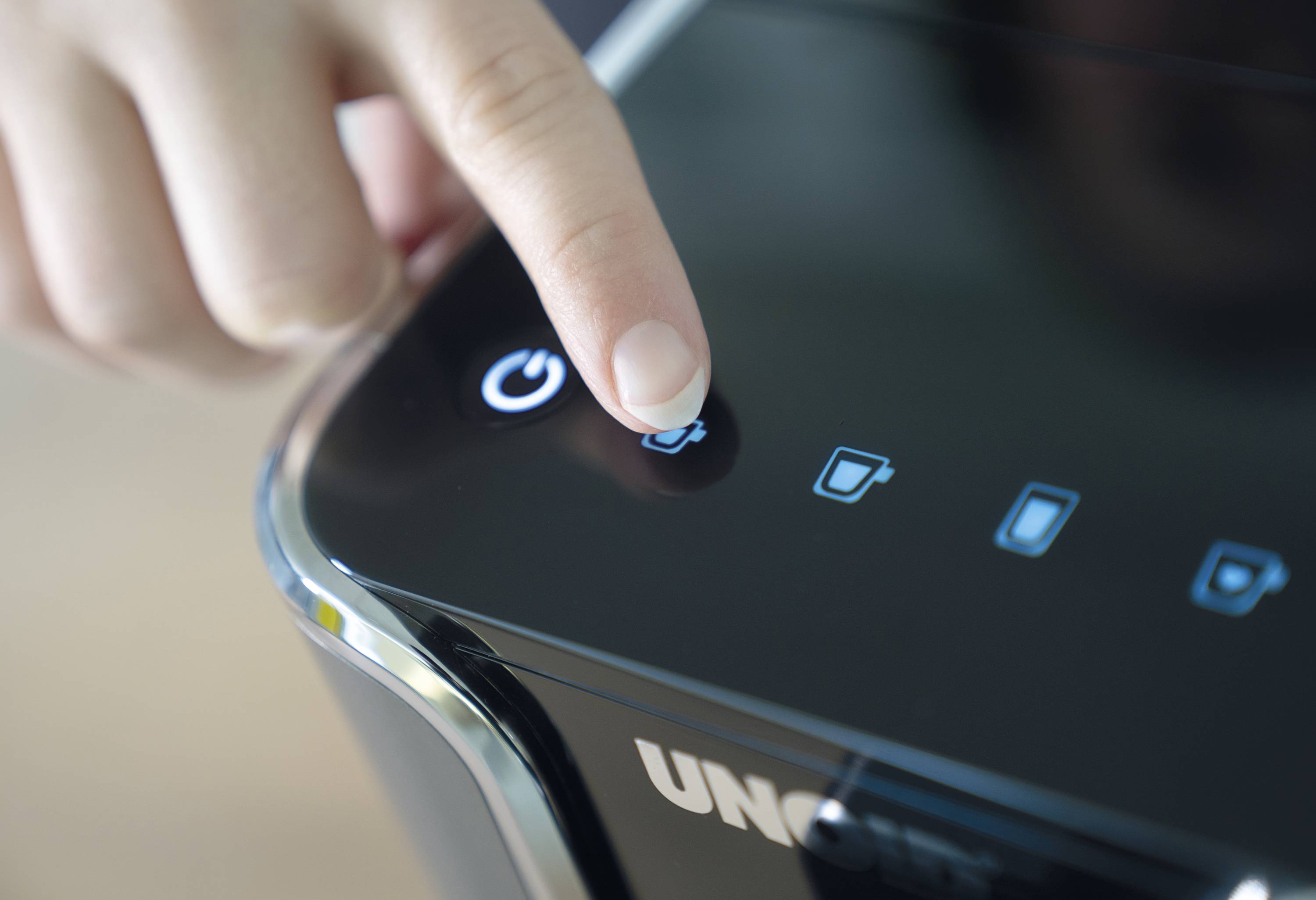 A hand presses the power button on an electrical device.