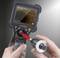 A person is holding an inspection camera with a screen displaying the interior of an object.