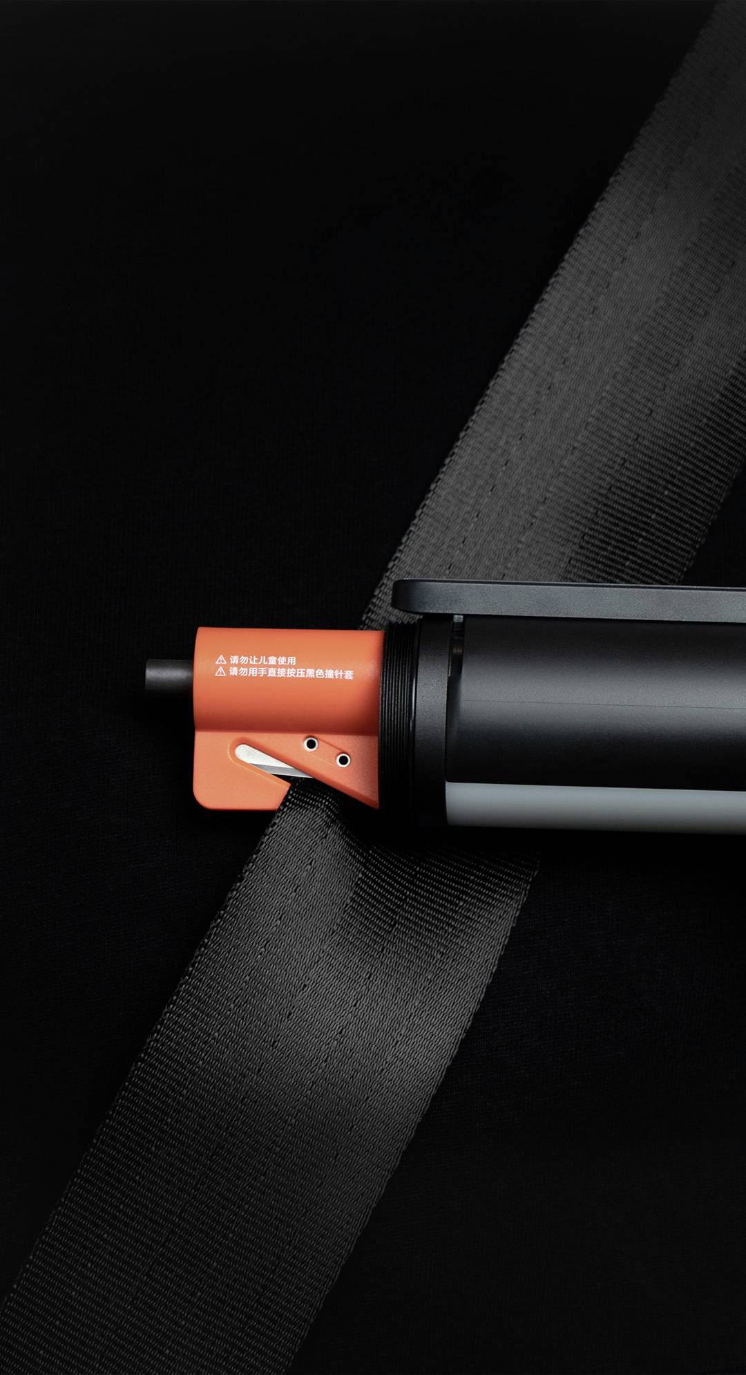 A black safety belt is stretched over a modern device with a red lever. The device is attached to a seat.