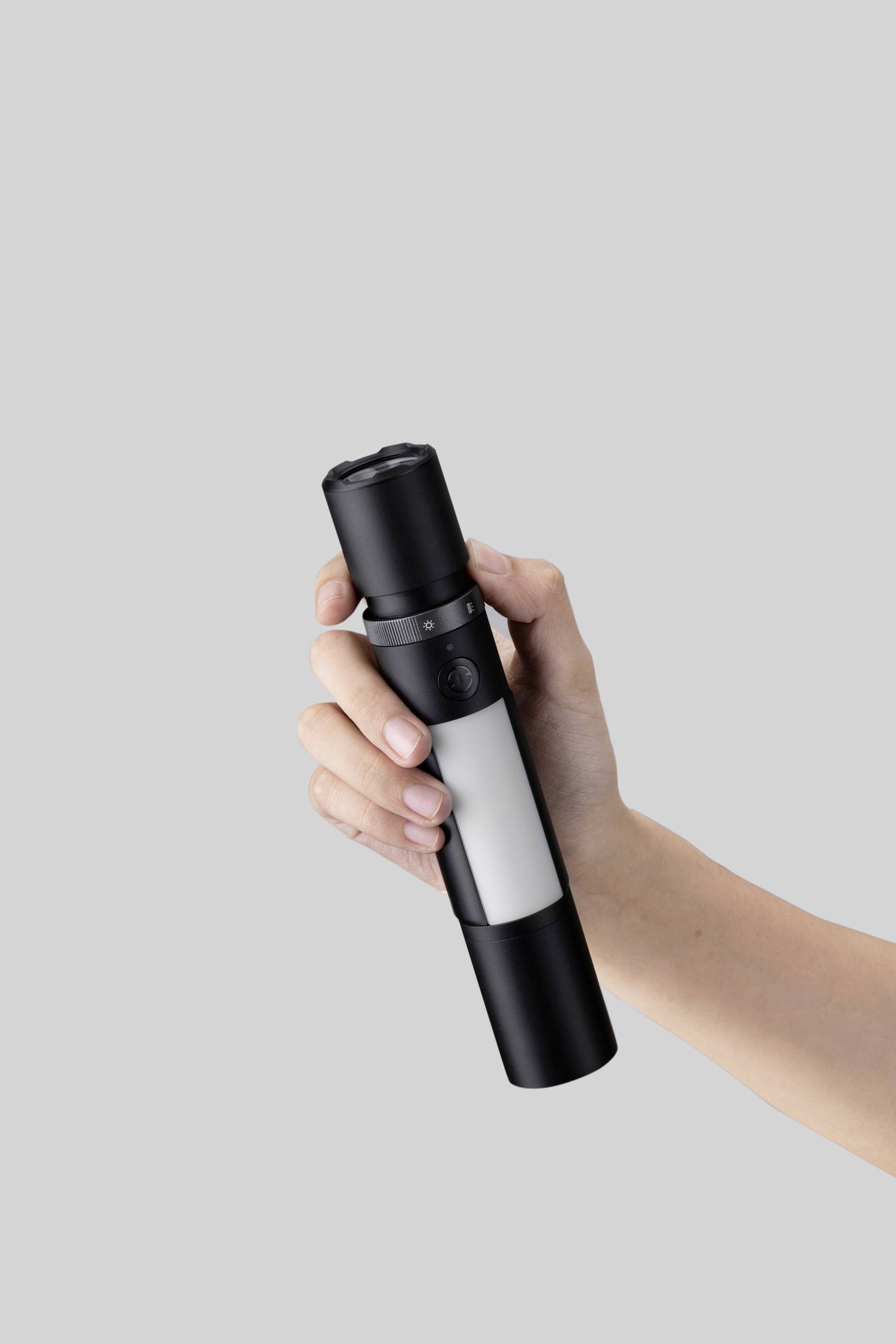 A hand holds a stylish black and white torch against a grey background.<br><br>Note: In British English, "torch" is used instead of the American "flashlight" for a handheld lighting device.