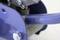 Close-up of a machine component with a blue metal part and screw, in an industrial setting.