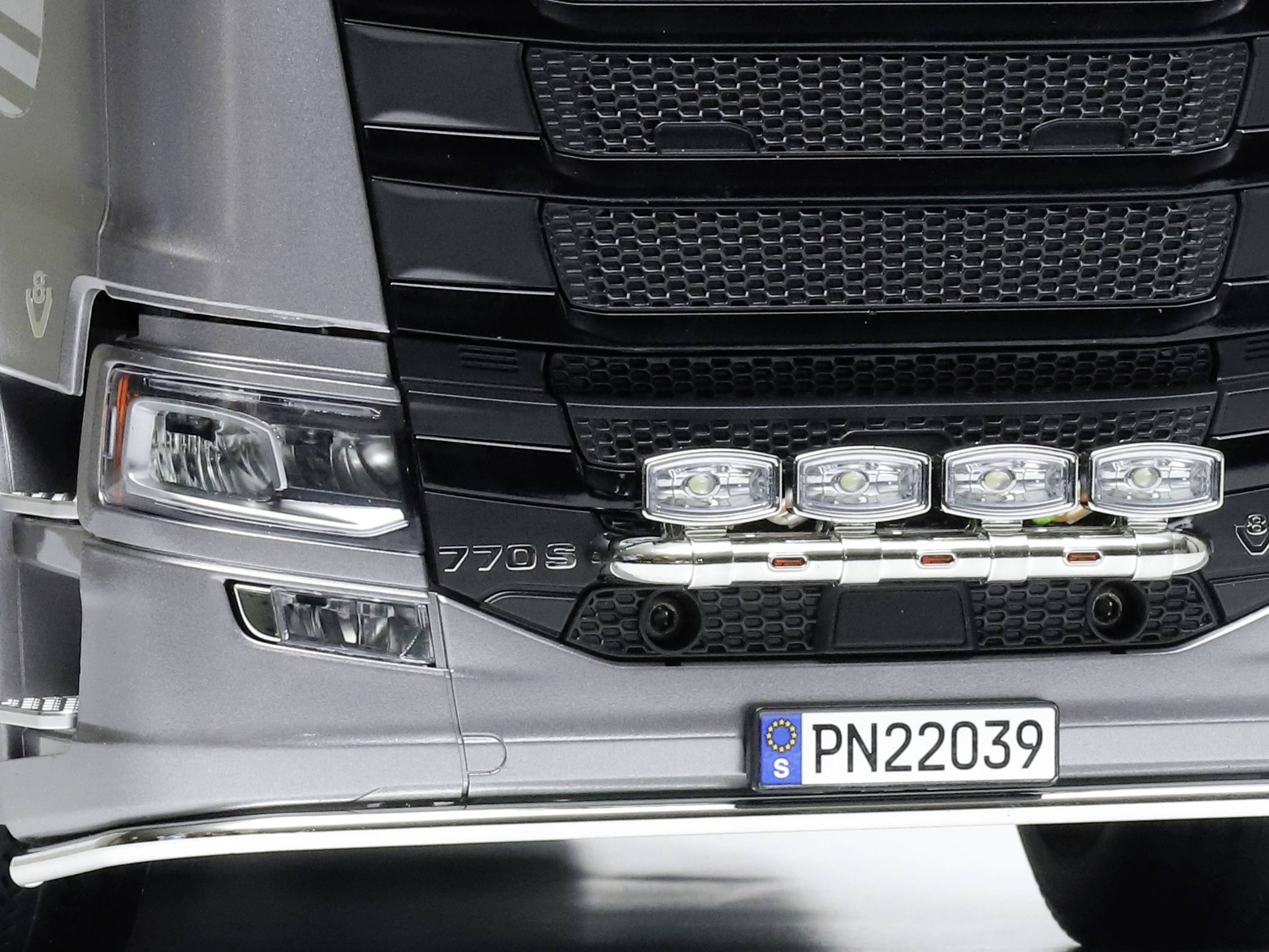 'Close-up of the front of a lorry with four large auxiliary headlamps and a numbered licence plate PN22039.'