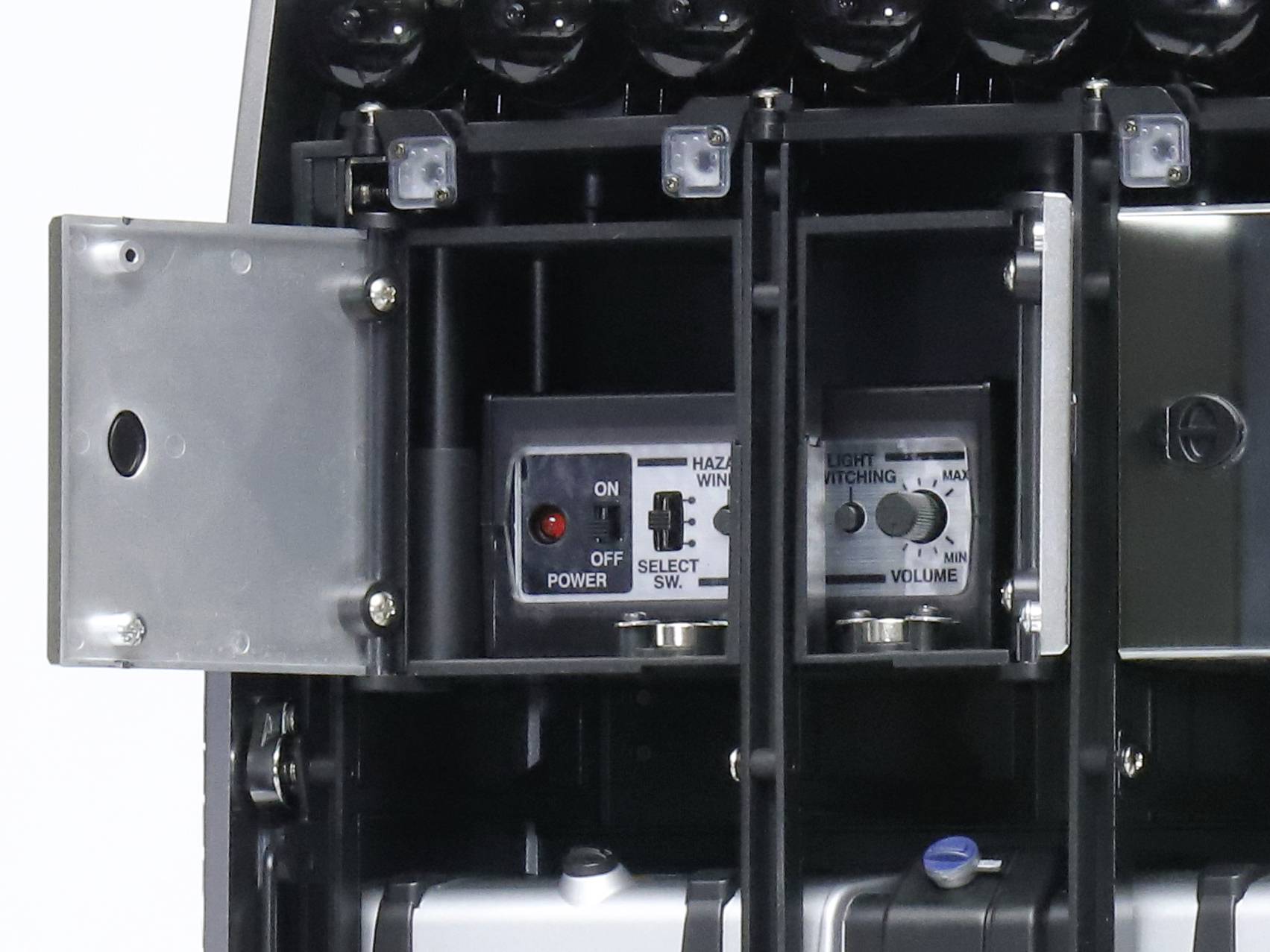 'Close-up of an opened control panel of a technical device with switches for power, selection, and volume.'