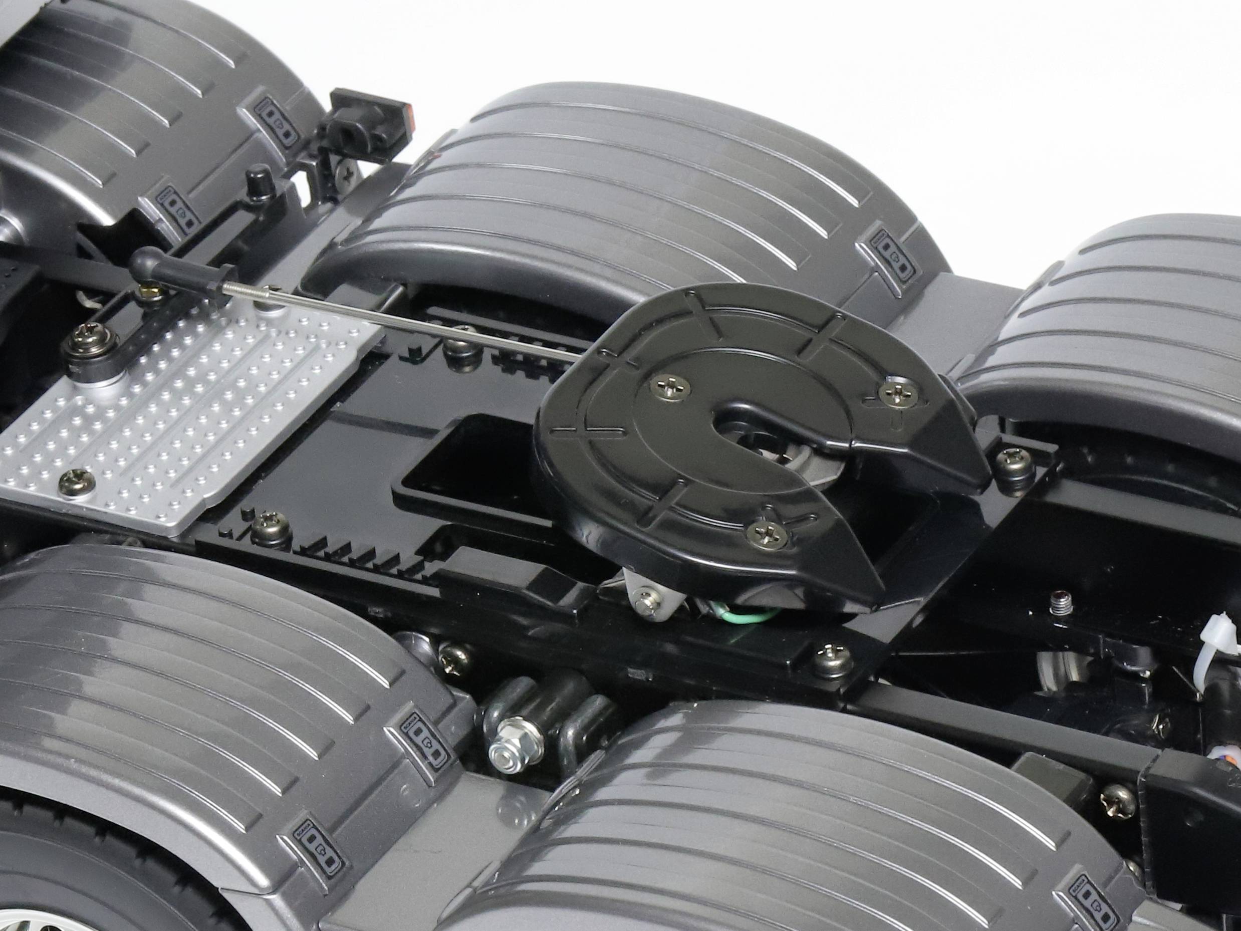 Close-up of a model lorry chassis made of plastic with eight wheels and a black frame.