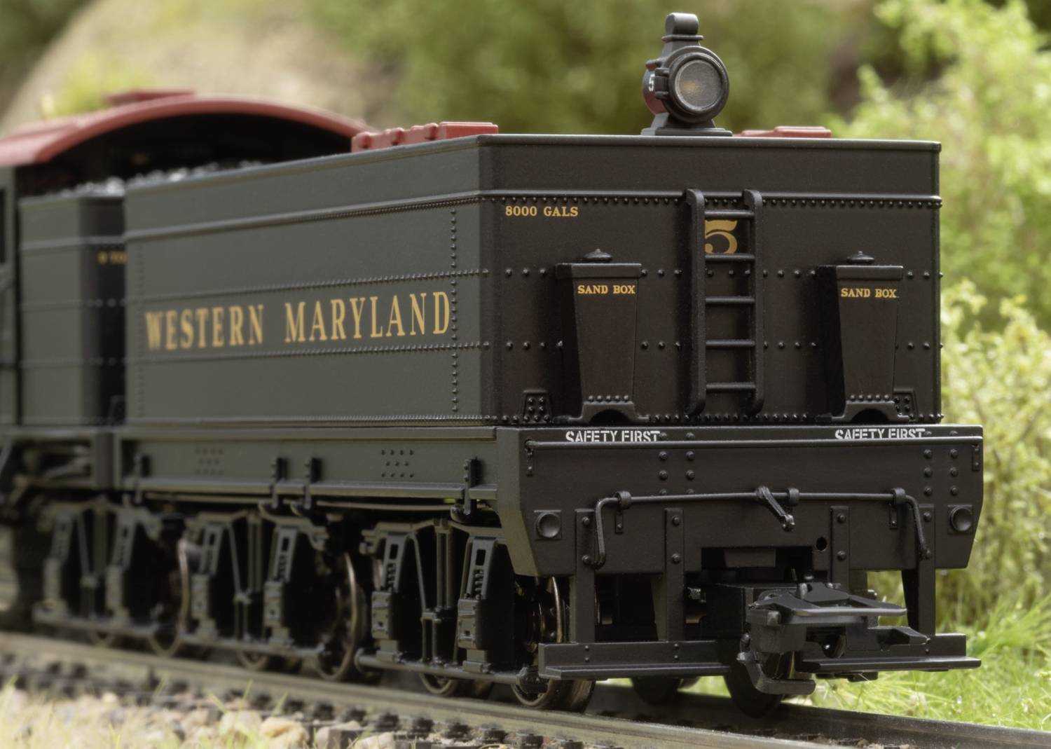 Model railway train with 'Western Maryland' inscription on the side of the carriage, running on a track, with a green landscape in the background.