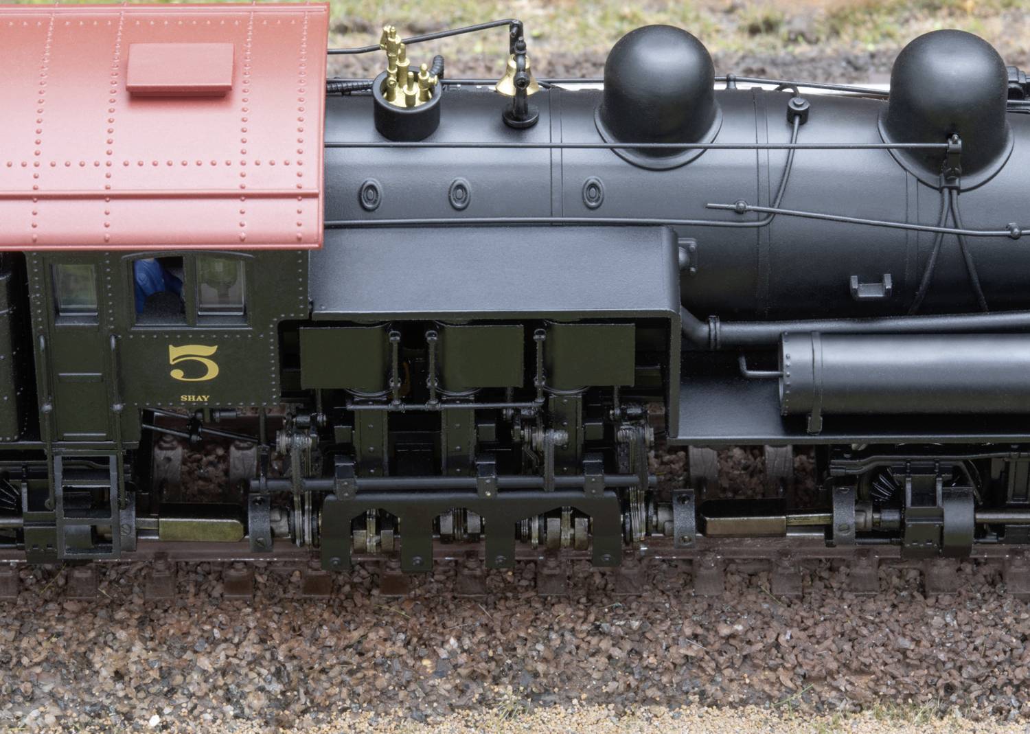 Black steam locomotive with a red roof on railway tracks, detailed view of wheels and boiler. Transport vehicle from the industrial era.
