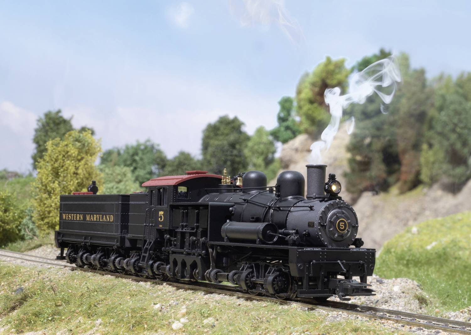 A black steam locomotive of the Western Maryland Railway travels along a rural route with a smoking chimney.