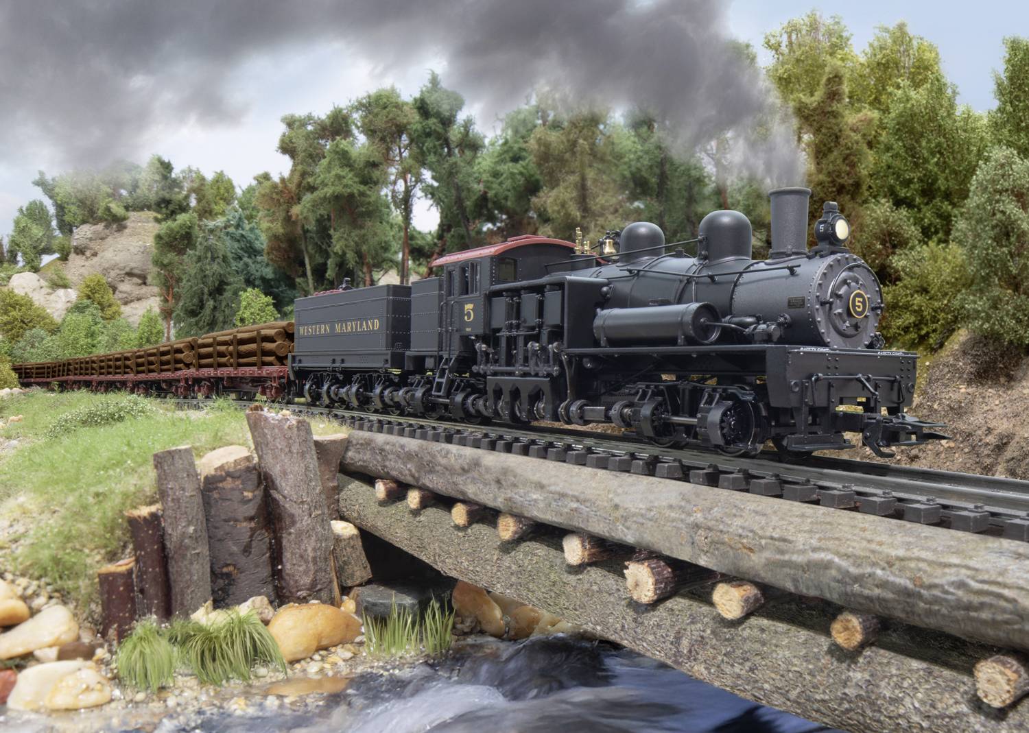 A black steam locomotive travels across a wooden bridge in a forested landscape. Smoke rises from its chimney.