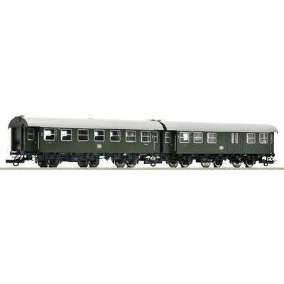 Two green, historic railway carriages with black wheels stand side by side. They have multiple windows and metal reinforcements.