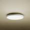 Round ceiling light emitting uniform, soft light onto a beige ceiling. Minimalist design, modern and elegant.