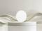 A round, white plinth set against a background of flowing, abstract wave lines. Subtle, modern aesthetic.