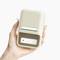 A hand is holding a small, beige electronic device box with a button and a flap, suitable for storing small objects.