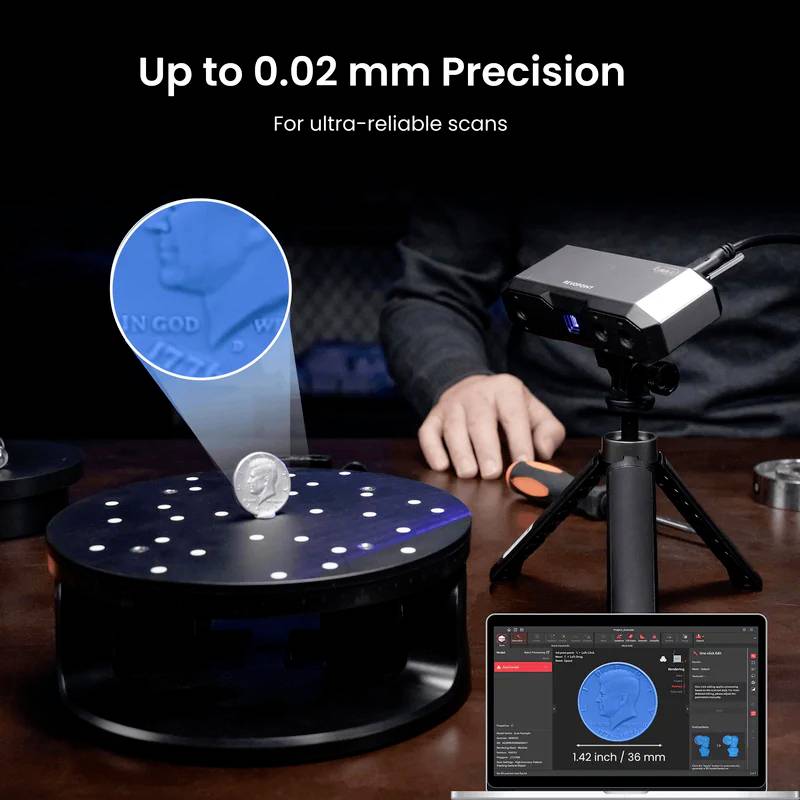 A person is scanning a coin with a scanner on a turntable; a 3D visualisation of the coin is displayed on a laptop screen.