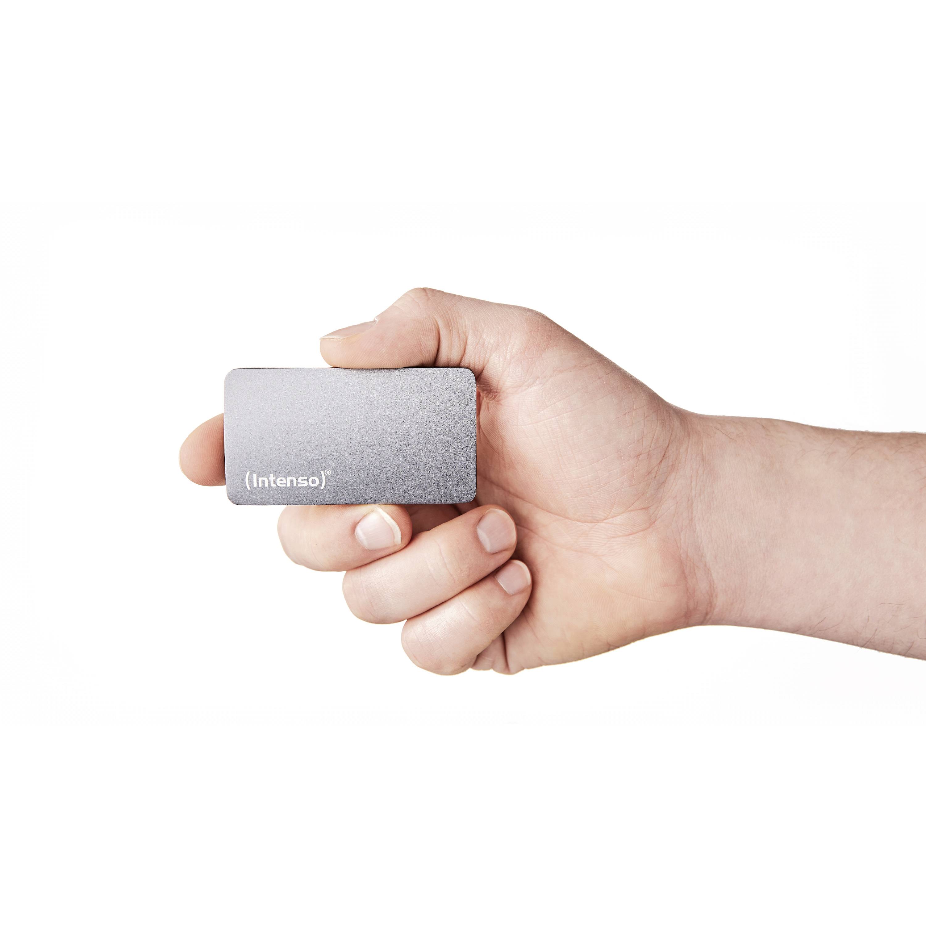 A hand is holding a small, grey external hard drive by the brand Intenso.