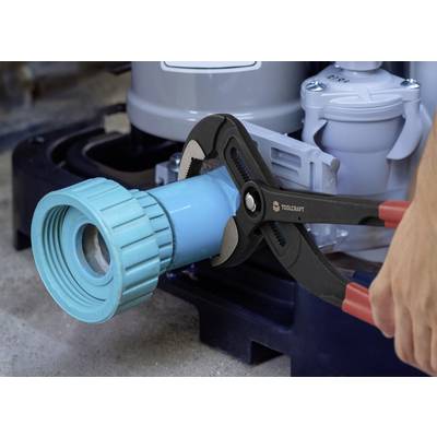 A person uses a large wrench to tighten a blue plastic pipe connector on industrial equipment, indicating maintenance or repair work.