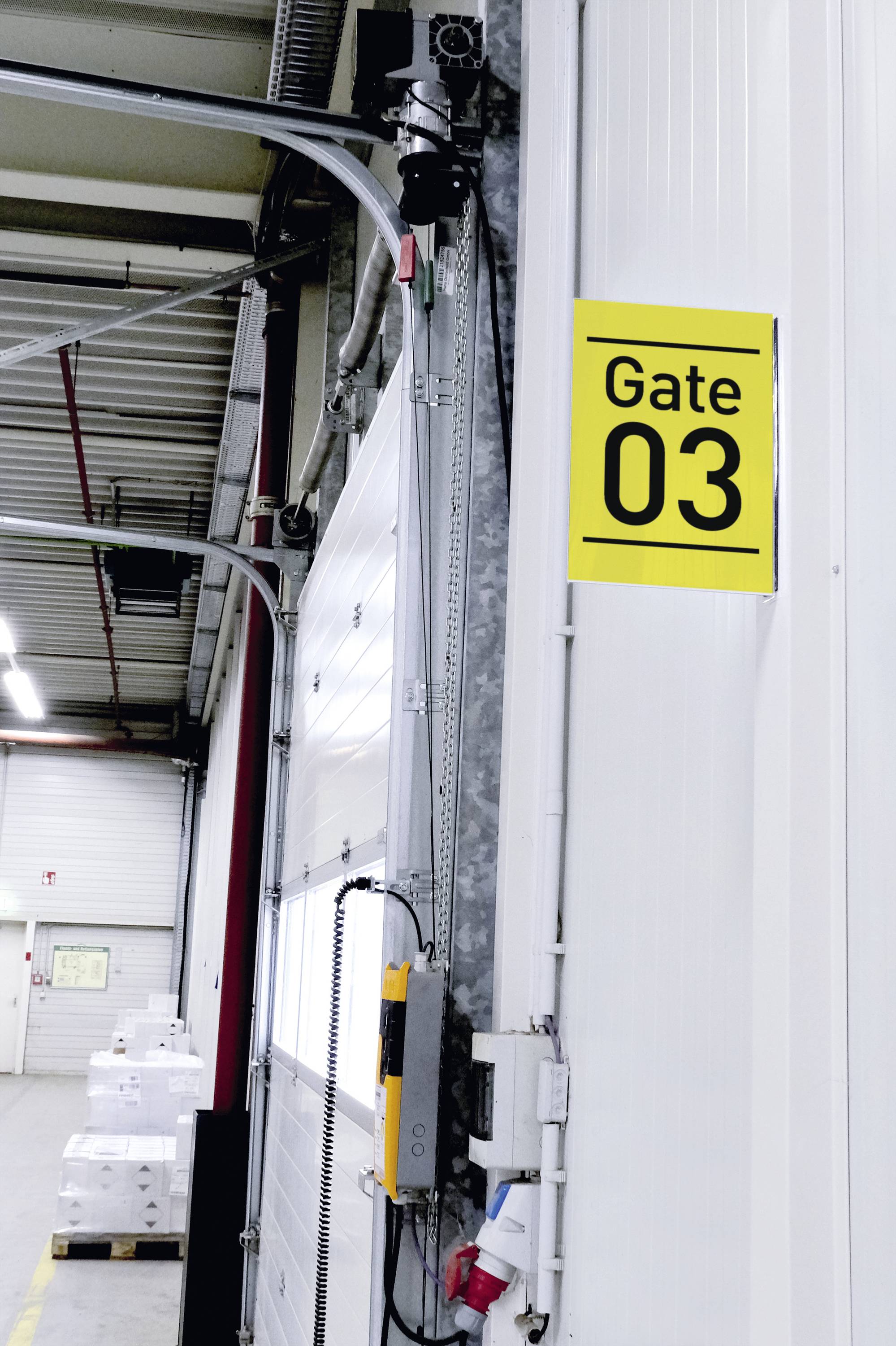 Warehouse with an open gate. A yellow sign reads 'Gate 03'. Stacked boxes are visible in the background.
