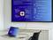 A laptop displays a presentation slide about the ChatGPT platform on a screen. The slide describes functions and features.