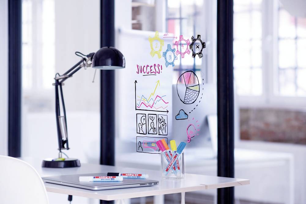 A desk with a lamp, pens, and glass graphics illustrating success, diagrams, and teamwork. Bright, modern office atmosphere.