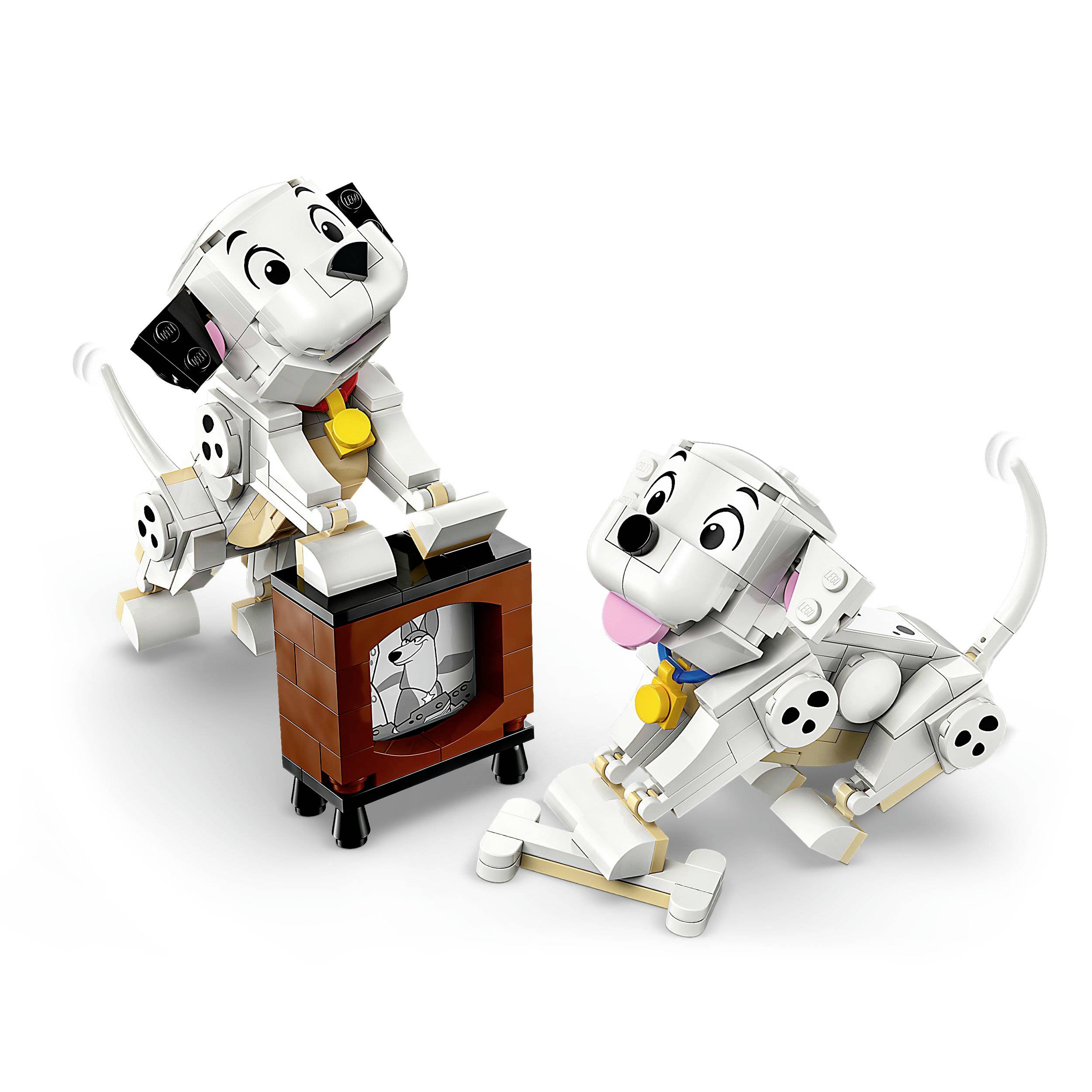 Two Dalmatian puppies made of LEGO bricks are playing cheerfully around a television. One dog is on its hind legs, the other is sitting.