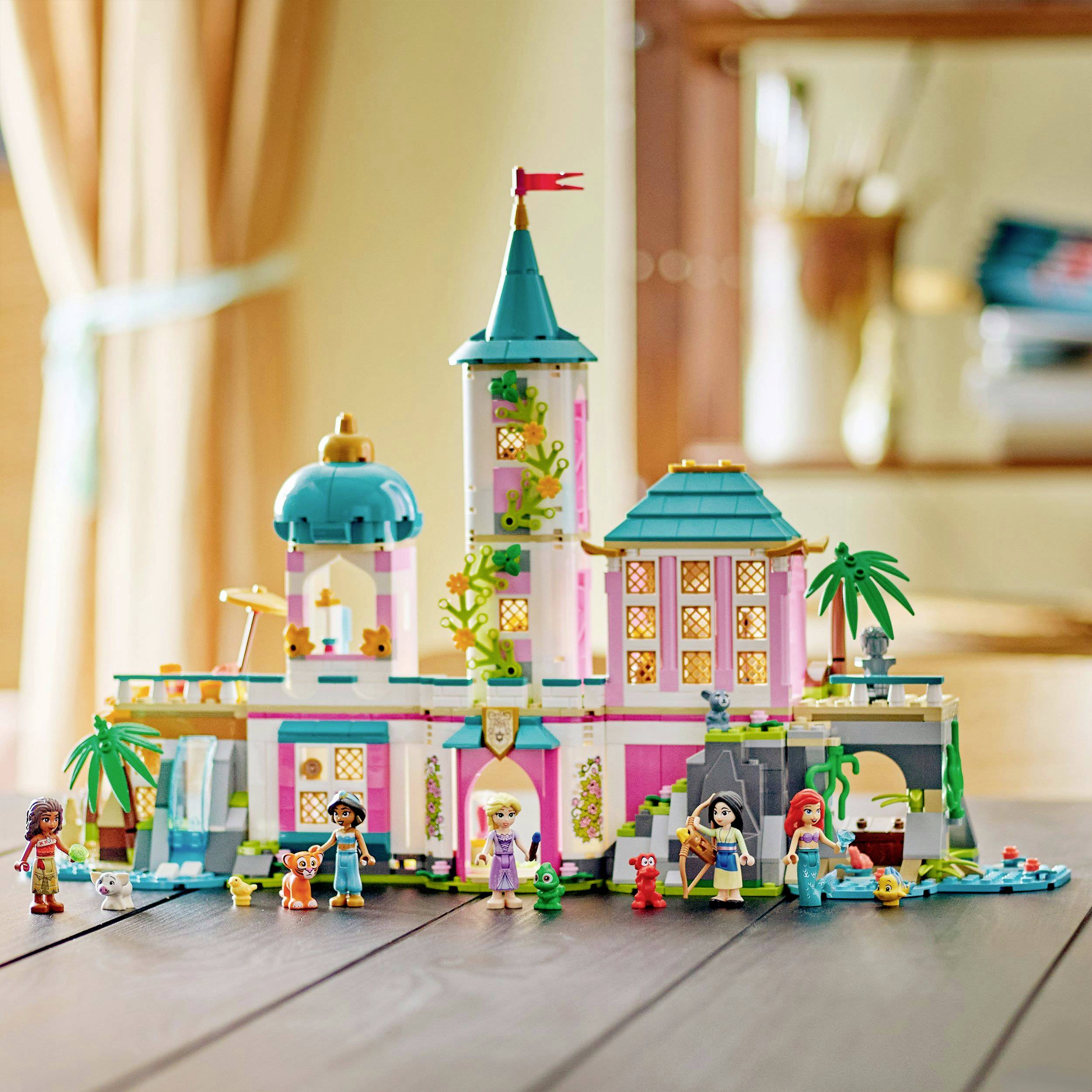 A colorful toy castle with towers and figures stands on a table, illuminated by soft daylight from a window.