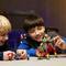 Two children are playing with colorful robot models on a table. They are smiling and concentrating on their constructions.