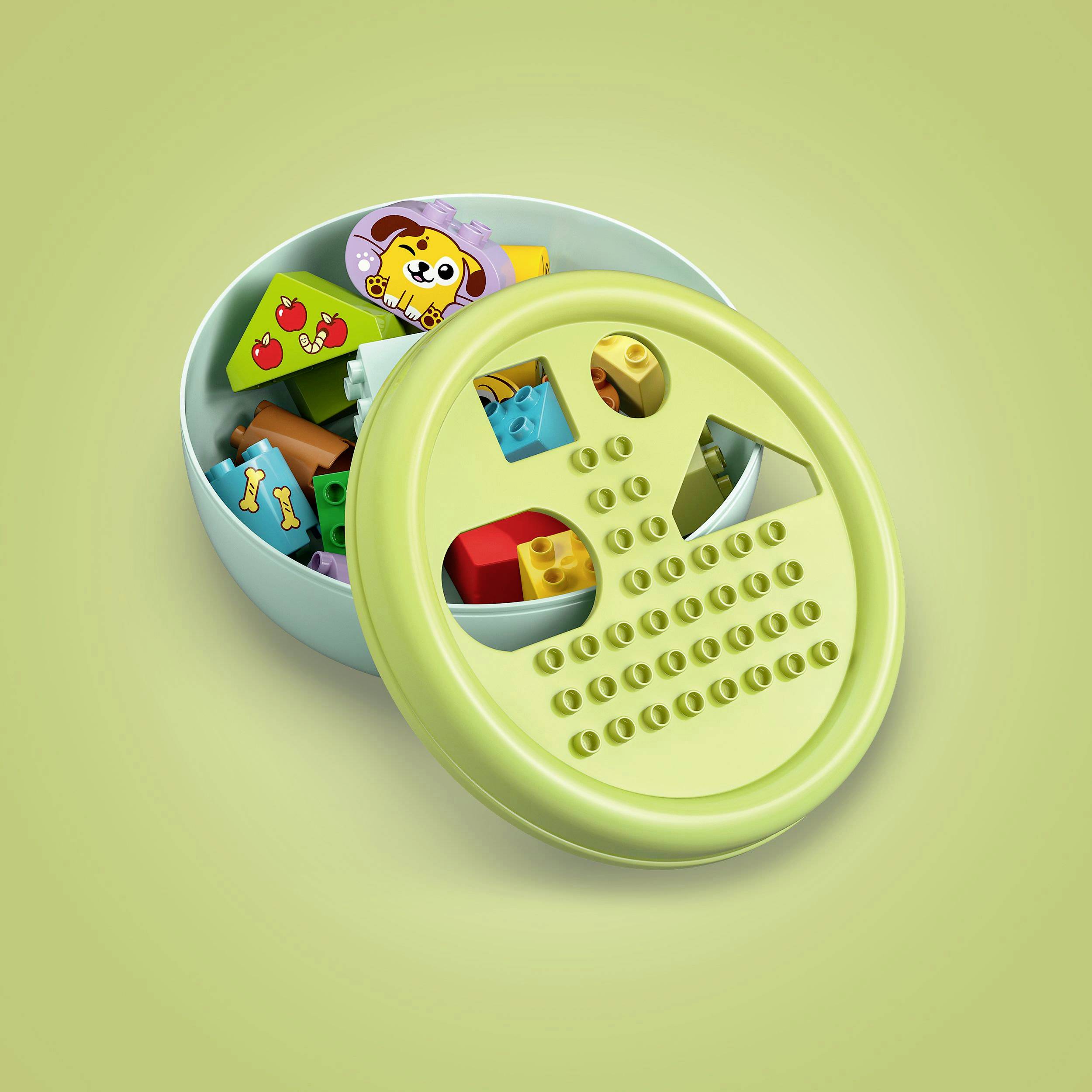A round, green toy box with various colorful building blocks and a lid with holes for sorting the shapes.
