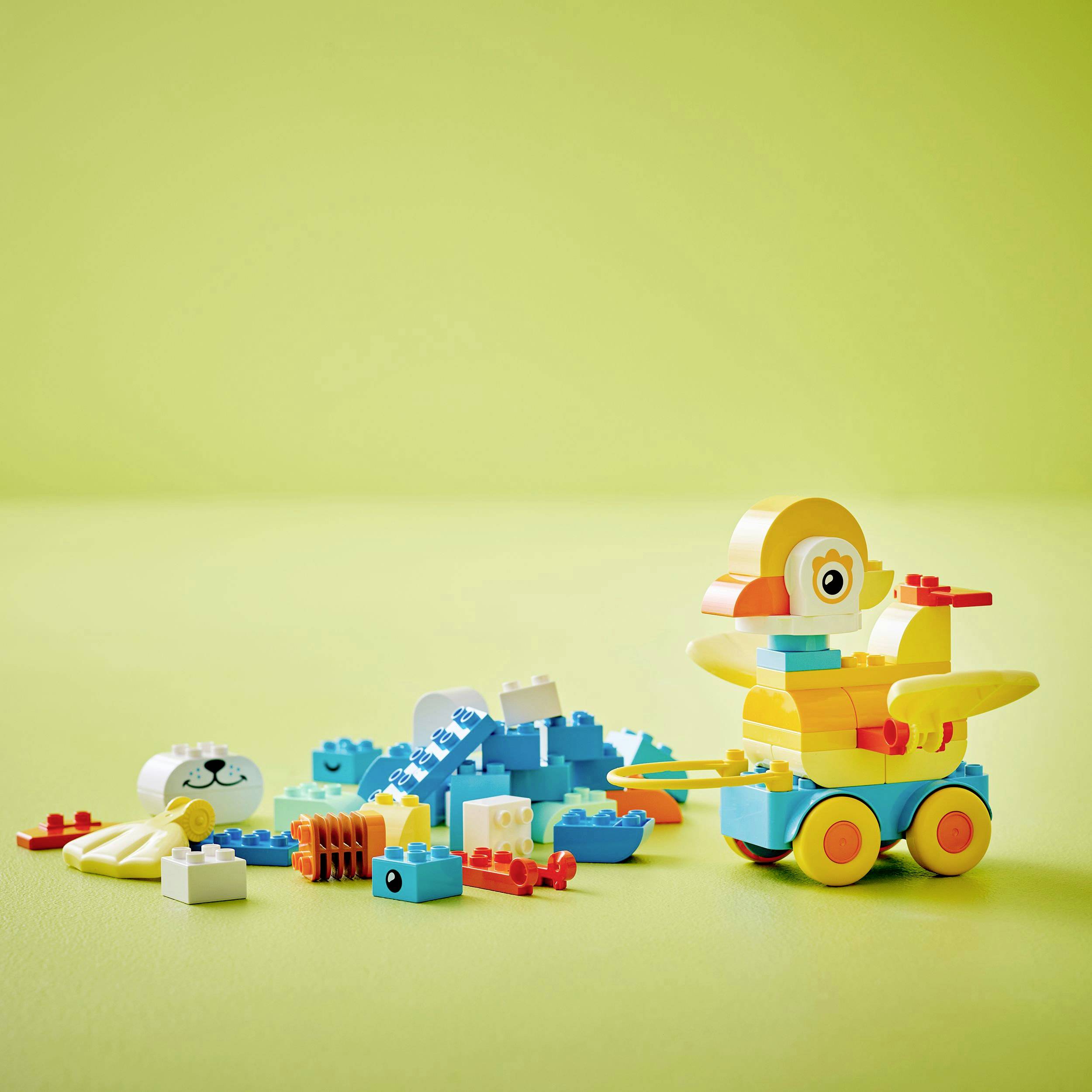 Colorful building blocks, some assembled as a duck on wheels and animals on a light background.
