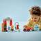 A child is playing with colorful building blocks and a small car on a table; they appear focused and happy.