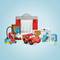 A red toy car stands in front of a building made of colorful building blocks. Tools and accessories are located next to it.