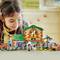 A child is playing with a colorful toy house made of building blocks. There are animals and figures that are part of the scenario.