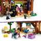 A dollhouse with figures in a kitchen and a horse stable, showing dolls baking, feeding animals, and a sleigh full of straw.