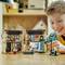 A boy plays intently with a dollhouse and figures in a cozily furnished room.