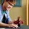 A man with glasses smiles and sits at the table, in front of him stands an Iron Man figure made of LEGO with a small sign.