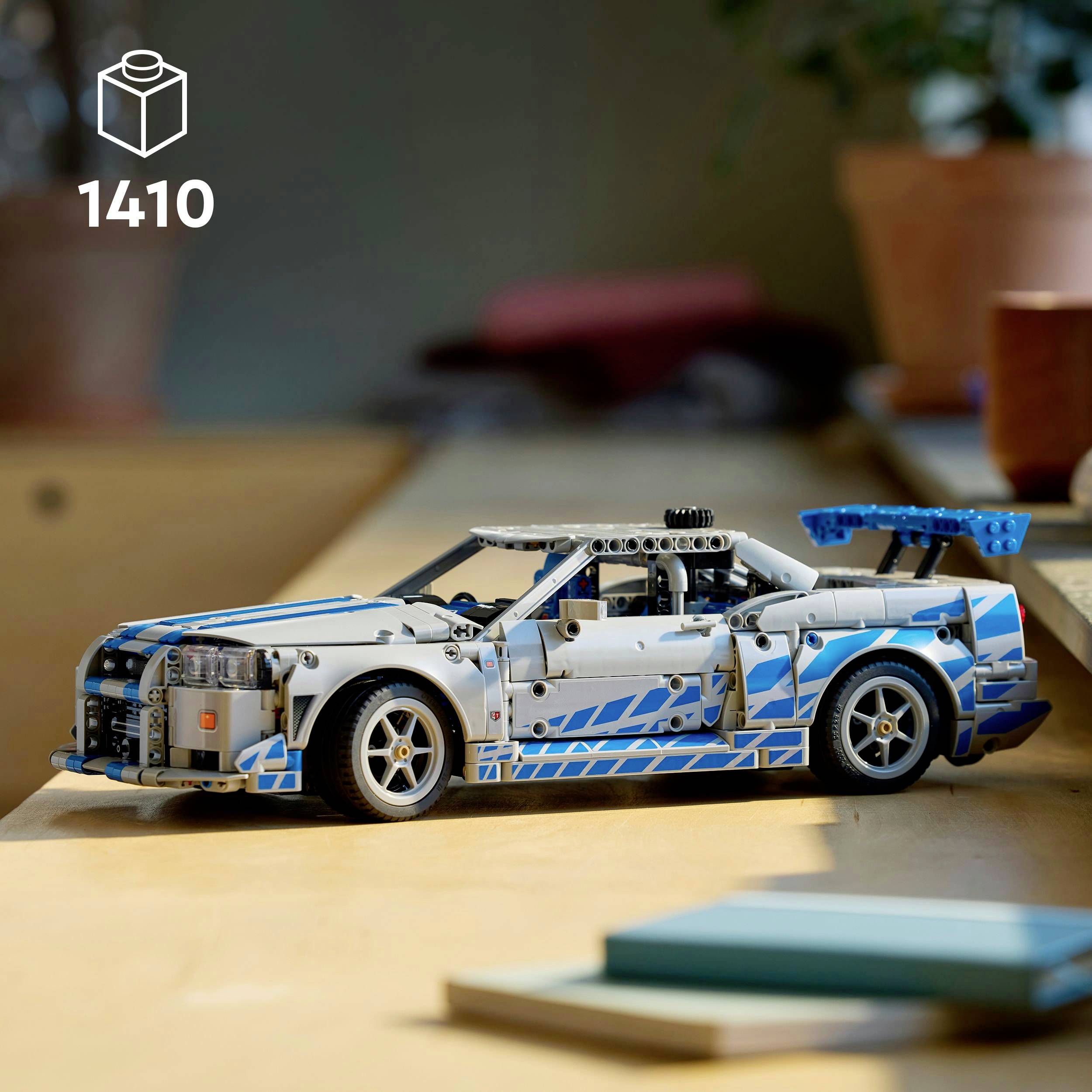 A detailed model of a racing car with blue accents on a wooden table. In the upper left, the number '1410' in white.