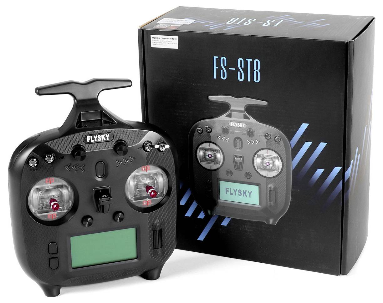 A black radio remote control with an LCD screen and two control sticks next to its matching packaging.