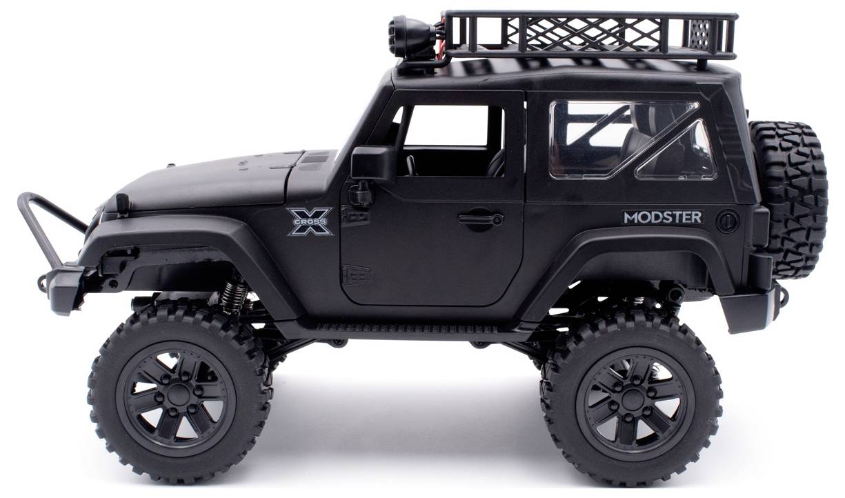 A black toy off-road vehicle in Jeep style with large tyres, a spare wheel, and a roof rack, photographed from the side.