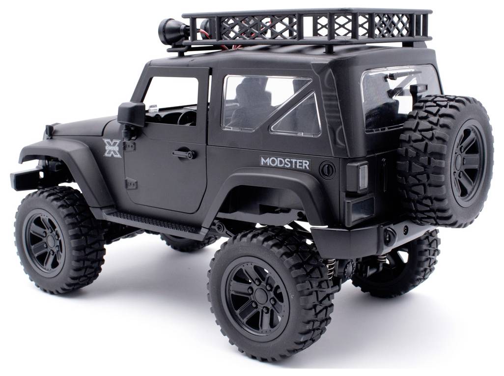 Black RC off-road model car with large tyres and roof rack, side rear view.