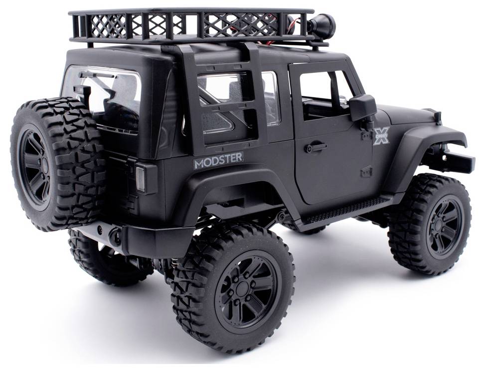 Black remote-controlled off-road vehicle with large tyres, spare wheel at the rear and roof rack, viewed from the side at the back.